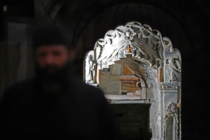 Un sacerdote ortodoxo griego se para delante de la Tumba de Jesús en el Sagrado Sepulcro.