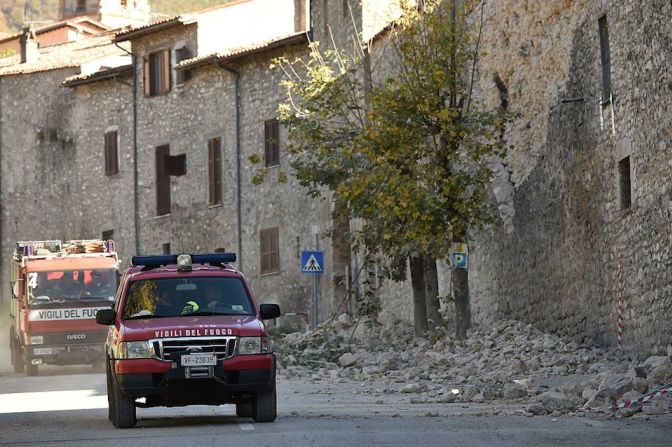 Bomberos pasan por una calle en Norcia, donde se ven apilados escombros tras el terremoto.