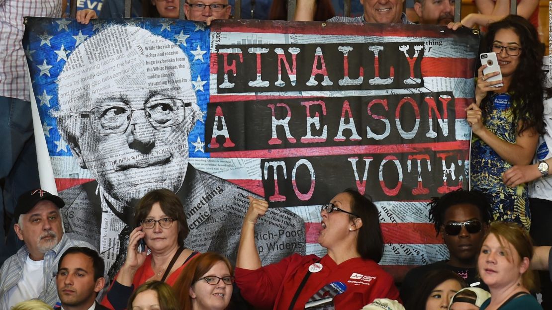 Seguidores de Bernie Sanders sostienen un afiche durante un evento de campaña del excandidato demócrata.