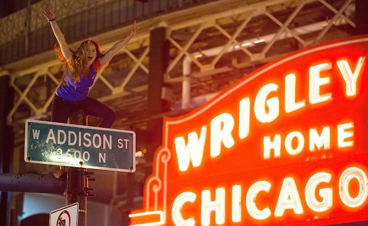 Una fanática del equipo de Chicago celebra la victoria encima de un poste en las calles de la ciudad.