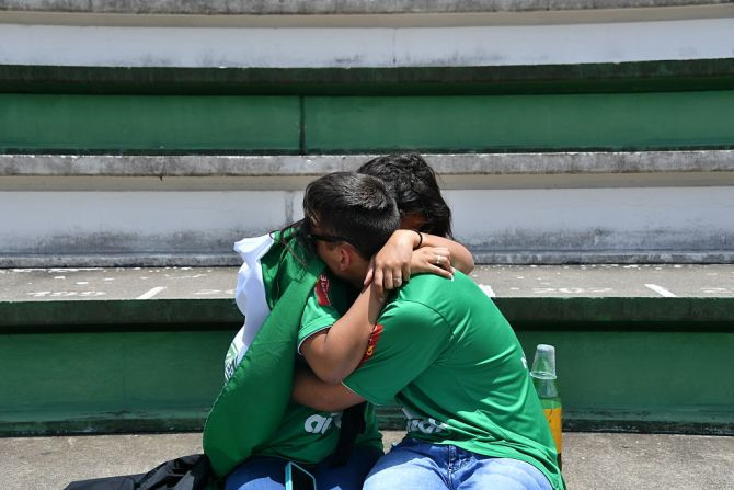 Dos hinchas se abrazan llorando durante el tributo.