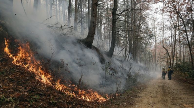 Los bomberos caminan sobre un sendero, mientras el incendio quema la ladera de una montaña en Clayton, Georgia, el pasado 15 de noviembre.