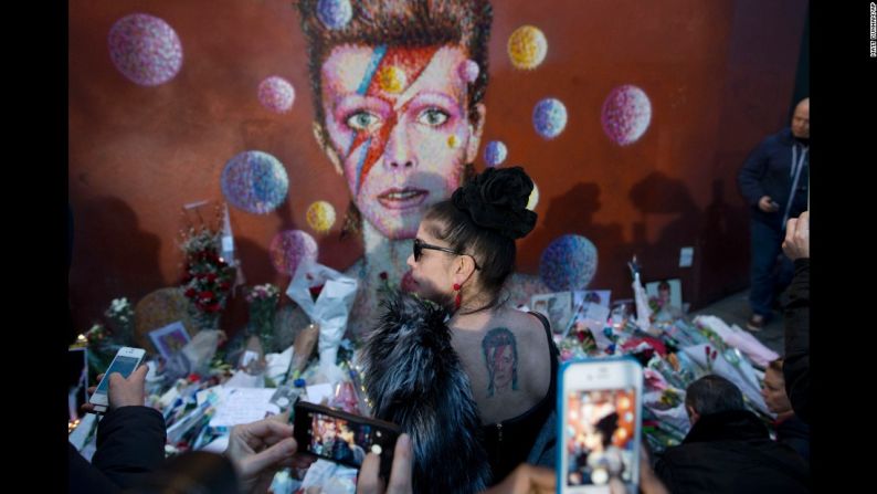 Enero 11: una mujer con un tatuaje de David Bowie posa frente a un mural en Londres. La leyenda del rock falleció un día antes tras una batalla de 18 meses contra el cáncer.