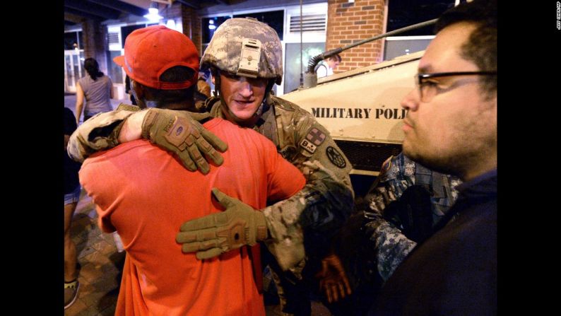 Septiembre 22: un manifestante abraza a un miembro de la Guardia Nacional en Charlotte, Carolina del Norte. Las protestas violentas surgieron en Charlotte tras la muerte de Keith Lamont Scott, quien recibió disparos por parte de la policía en un estacionamiento de un edificio de apartamentos. El jefe de policía de Charlotte-Mecklenburg Kerr Putney dijo que Scott salió de su auto con un arma y que le dispararon después de que se rehusó a soltarla. La familia de Scott dijo que no estaba armado y que estaba sentado en su auto leyendo un libro. Una investigación de dos meses determinó después de que la acción del policía que disparó estaba justificada y que "toda la evidencia creíble" llevaba a la conclusión de que Scott estaba armado. El fiscal del condado Mecklenburg Andrew Murray dijo que no llegó a la conclusión solo, sino que 15 fiscales acordaron de forma unánime la decisión.