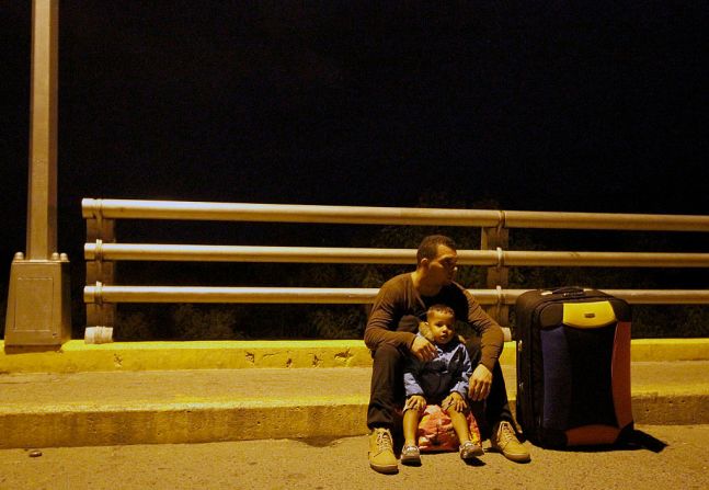 Un hombre y su hijo permanecen en el puente Internacional Simón Bolívar, en el lado colombiano de la frontera tras el cierre de la frontera.