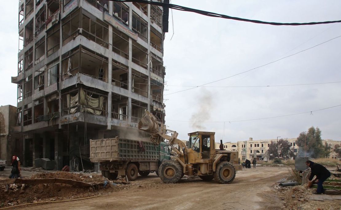 TOPSHOT - A bulldozer removes rubble from a road as Syrian pro-government forces re-open a street in Aleppo's old city that was formerly barricaded, dividing the government-held and rebel-held areas of the city on December 17, 2016.  / AFP / Youssef KARWASHAN