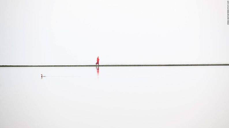 West Kirby, Wirral, Reino Unido – La península de Wirral en el noroeste de Inglaterra es la escena de esta inusual imagen tomada por Craig Easton. Aquí se muestra un solitario monje budista en la pared del límite del lago. La serie de imágenes de Easton desde Wirral, le hizo llevarse el premio mayor en la categoría de portafolio de Tierra, Mar y Cielo.