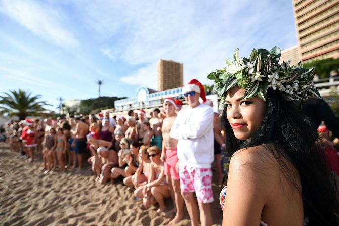 Una bailarina de Tahití posa junto a un grupo de personas que participan en un baño anual en Mónaco.