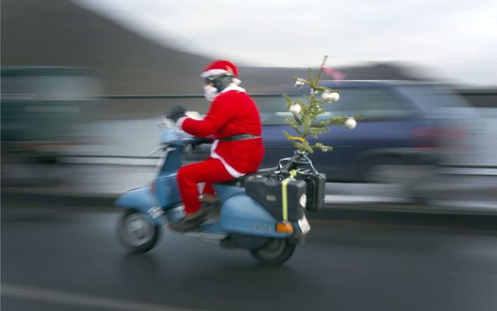 Un hombre disfrazado de Santa Claus conduce una motocicleta en camino a un encuentro anual de motociclistas.