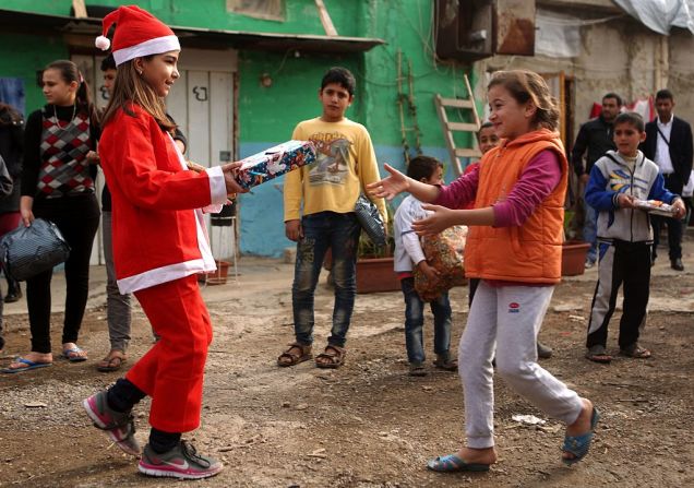 Chloe, una adolescente libanesa vestida como Santa Claus le entrega un regalo a una adolescente refugiada siria.