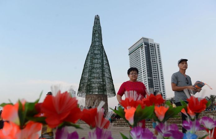 Transeúntes en Sri Lanka caminan frente a un árbol de Navidad parcialmente construido.