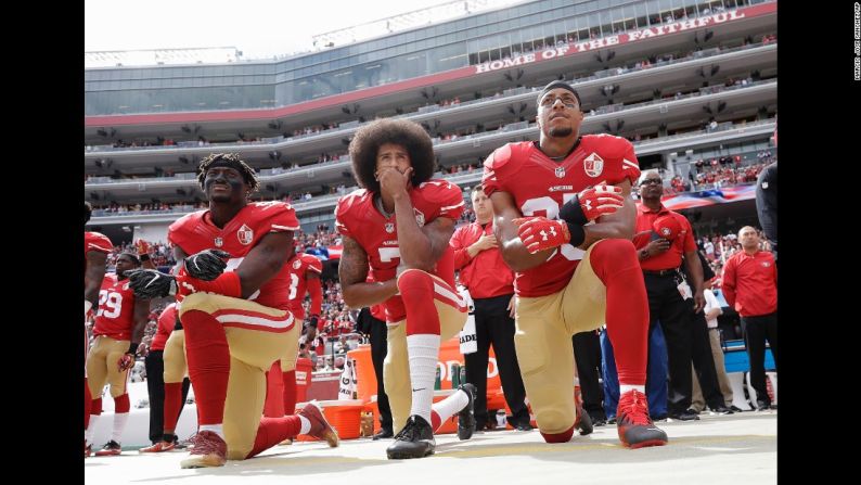 De izquierda a derecha, los jugadores de los San Francisco 49ers Eli Harold, Colin Kaepernick y Eric Reid se arrodillan para protestar durante el himno nacional el 2 de octubre. Desde el principio de la temporada, Kaepernick se ha negado a estar de pie durante el himno pues dice que no mostrará "orgullo por una bandera de un país que oprime a las personas negras y de color".