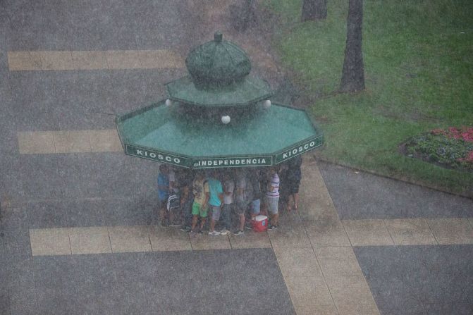 Personas se refugian de la lluvia en la Plaza Independencia en Montevideo.