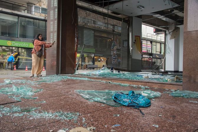 Una mujer toma una foto de un negocio afectado frente a la Plaza Independencia en Montevideo.