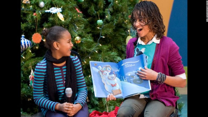 Malia y Sasha leen un libro a los niños durante una visita a un hospital en Washington en diciembre de 2009.