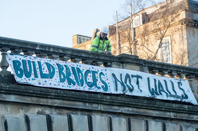 Un hombre en Bath, Inglaterra, para a observar un cartel que dice “Construyan puentes no muros”. Este cartel hace parte de una serie de eventos alrededor del mundo para expresar la desaprobación de la toma de posesión de Donald Trump.