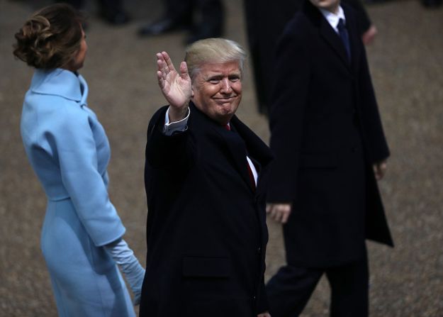 El presidente de Estados Unidos, Donald Trump, saluda a la multitud mientras camina por la ruta del desfile inaugural, acompañado de la primera dama.