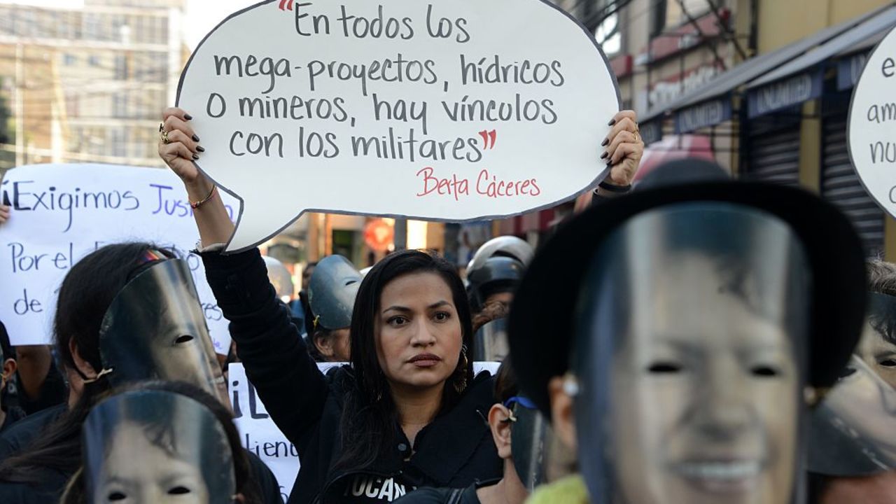 A woman holds a banner reading "In all water or mining mega-projects, there are links with military men" during a protest in demand of justice for indigenous Honduran environmental activist Berta Caceres' murder on the Women's Day in Tegucigalpa on January 25, 2017.  / AFP / ORLANDO SIERRA