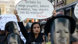 A woman holds a banner reading "In all water or mining mega-projects, there are links with military men" during a protest in demand of justice for indigenous Honduran environmental activist Berta Caceres' murder on the Women's Day in Tegucigalpa on January 25, 2017.  / AFP / ORLANDO SIERRA