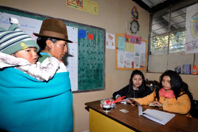 Una mujer indígena —que lleva a su hijo en la espalda— vota en el colegio José Acosta Vallejo en la ciudad de Cangahua, Ecuador, durante la elección general en la que Ecuador elige al sucesor de Rafael Correa.