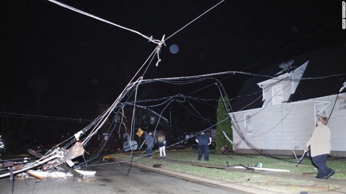 Personas caminan entre cables caídos después de que una tormenta pasara por Naplate, el martes.