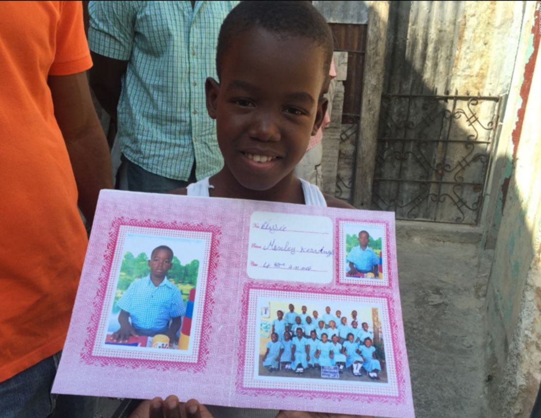 Monley Elysee sostiene una foto suya en el colegio en el que estudia, en Puerto Príncipe.