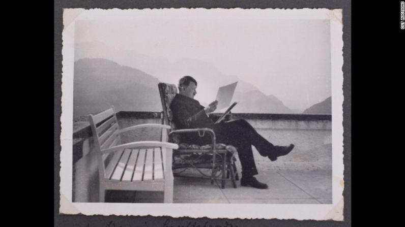 Hitler se sienta cómodamente en una silla en la terraza de su villa en el sur de Alemania, leyendo un documento.