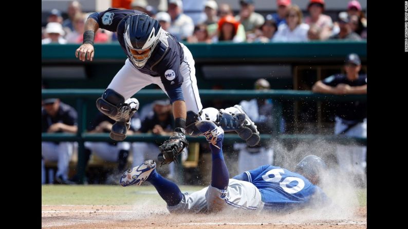 Jon Berti, de Toronto, se desliza seguro hacia la base ante la presencia de Álex Ávila, catcher de Detroit, durante un juego de entrenamiento en Lakeland, Florida, el viernes 19 de marzo.