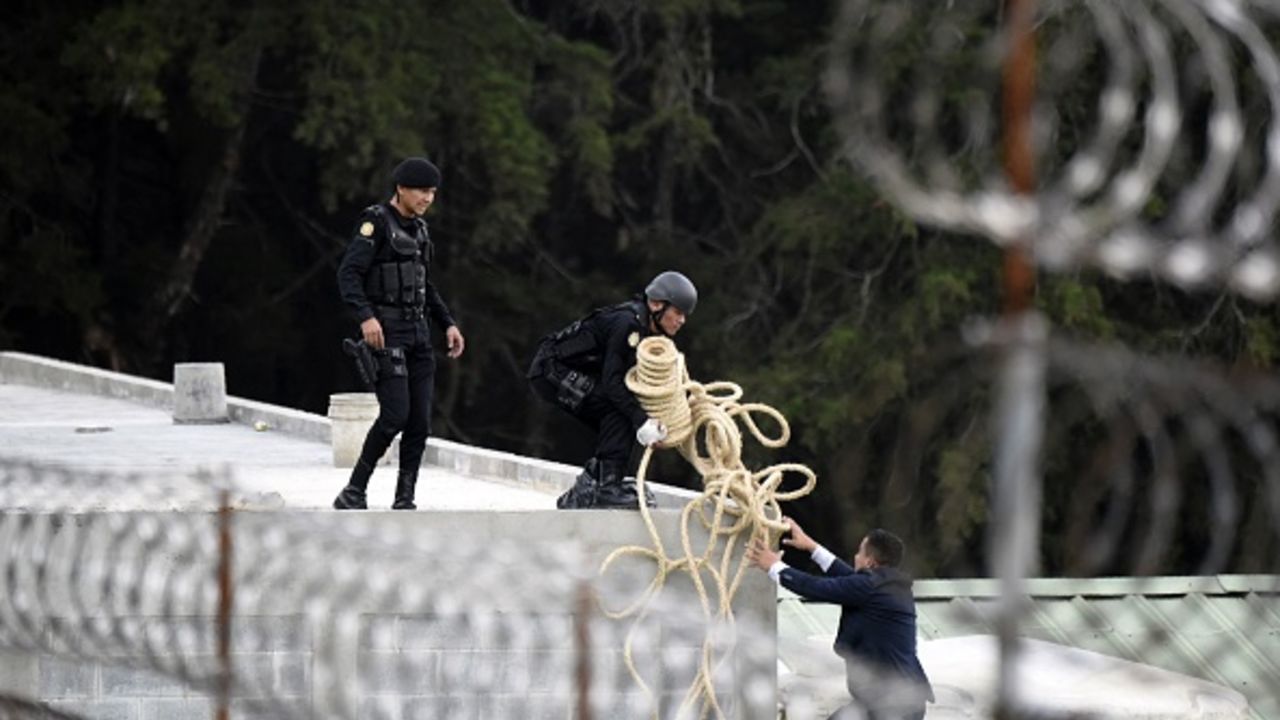 Riot police agents carry a roll of rope atop a roof during the operative to rescue the four hostages kept held by inmates at the Stage II Male Juvenile Detention Center in San Jose Pinula, east of Guatemala City, on March 20, 2017.
Guatemalan police stormed a juvenile detention center outside the capital Monday to free four guards taken hostage by inmates who had killed two others during a riot. / AFP PHOTO / JOHAN ORDONEZ