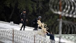 Riot police agents carry a roll of rope atop a roof during the operative to rescue the four hostages kept held by inmates at the Stage II Male Juvenile Detention Center in San Jose Pinula, east of Guatemala City, on March 20, 2017.
Guatemalan police stormed a juvenile detention center outside the capital Monday to free four guards taken hostage by inmates who had killed two others during a riot. / AFP PHOTO / JOHAN ORDONEZ