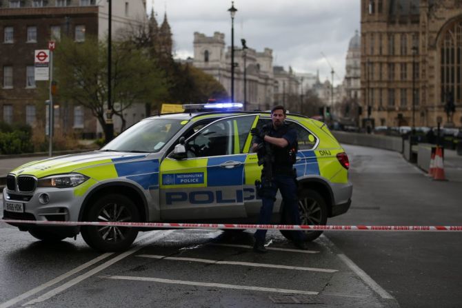 Un policía armado monta guardia junto a una patrulla a las afueras del Parlamento británico. La zona está acordonada.