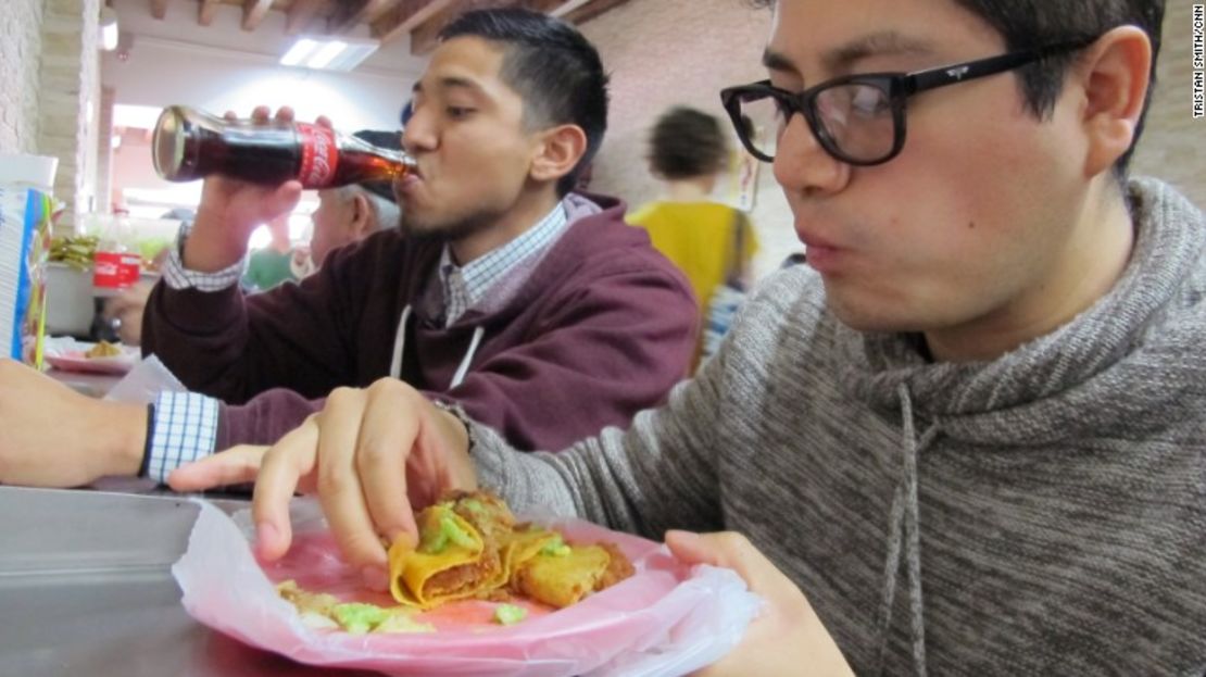 Matadamas, a la izquierda, y su primo Daniel Velasco mientras comen en un puesto de tacos.