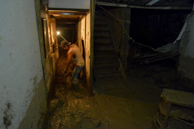 Un hombre limpia el lodo que invadió su casa.