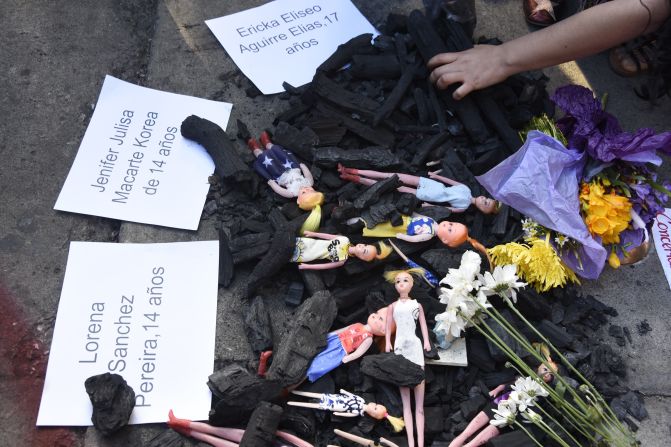 Muñecas que representan las víctimas del hogar seguro Virgen de la Asunción se ven entre carbones y acompañadas de carteles durante una manifestación denominada "Guatemala no es un hogar seguro" en Ciudad de Guatemala el 9 de marzo del 2017. JOHAN ORDÓÑEZ/AFP/Getty Images)