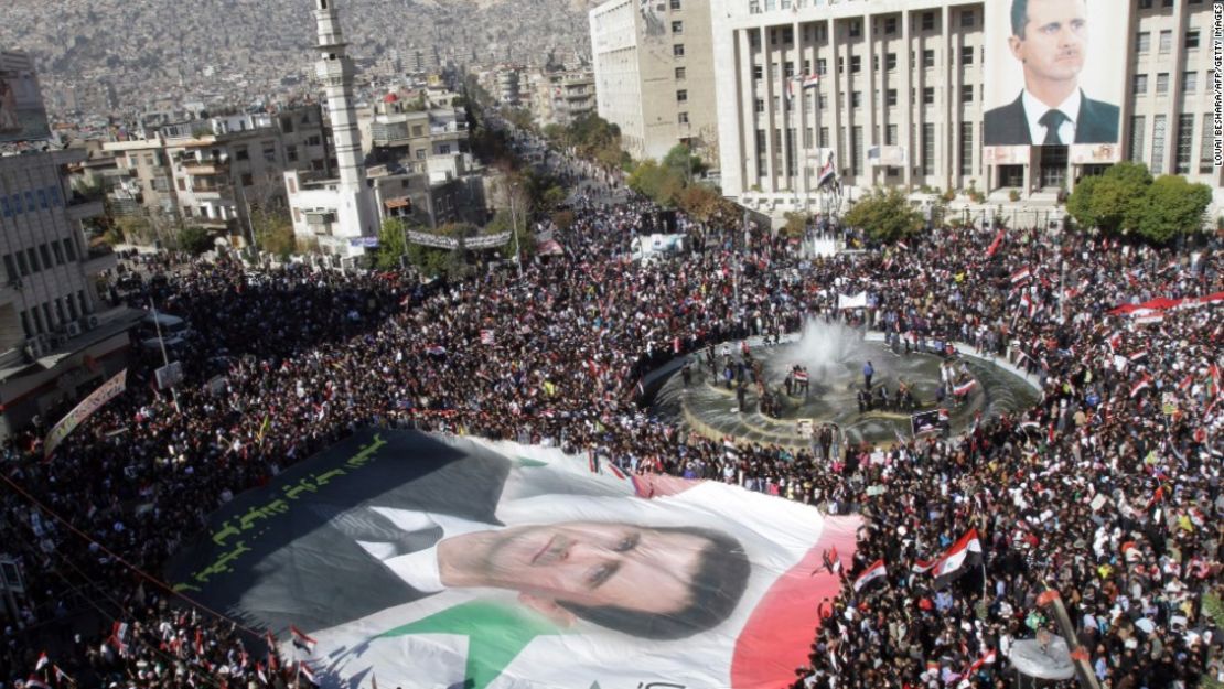 Manifestantes sirios cargan una bandera enorme del presidente Bashar al-Assad, el 28 de noviembre del 2011 en Damasco. Protestan en contra de la decisión de la Liga Árabe de imponer duras sanciones al régimen sirio.