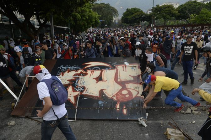 Activistas de la oposición bloquean el paso de las fuerzas antimotines con una guarimba improvisada.