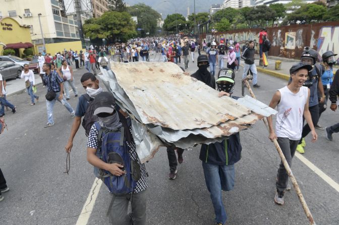 Manifestantes trasladan láminas de zinc para construir guarimbas.