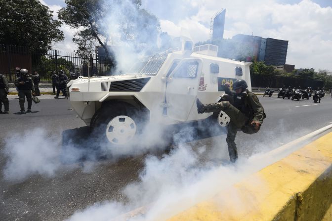 Miembro de la Guardia Nacional de Venezuela patea una lata de gas lacrimógeno.