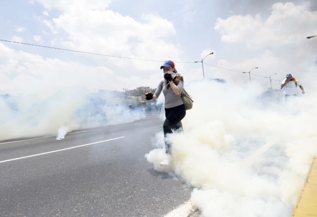 Dos manifestantes tratan de evitar los gases lacrimógenos lanzados por la GNB.