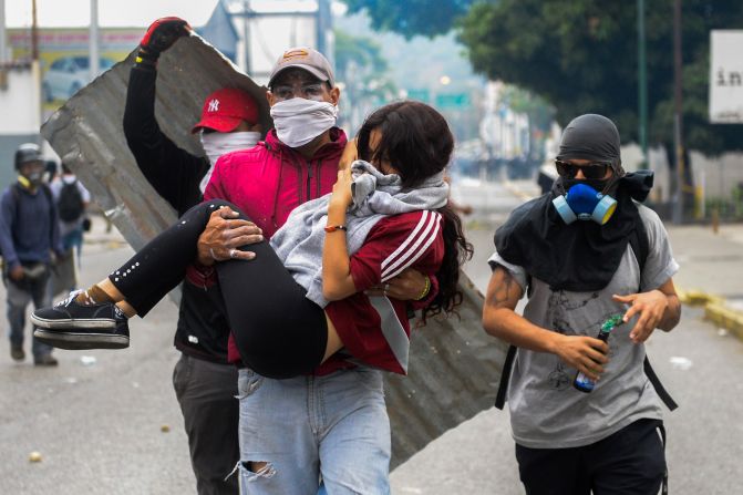 Una joven es trasladada por manifestantes tras ser dispersados por bombas lacrimógenas.