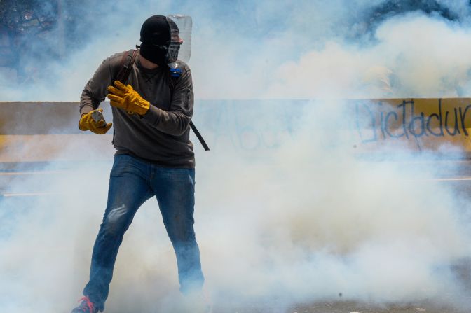 Un manifestante con guantes y una máscara hecha con la mitad de una botella de plástico.