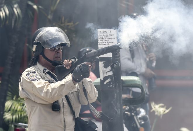 Un miembro de la Policía Nacional Bolivaria dispara una bomba lacrimógena a los manifestantes en Caracas.