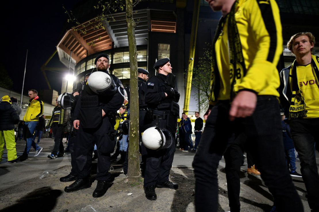 La policía observa a los fanáticos del Borussia Dortmund dejar el estadio Signal Iduna Park luego de la cancelación del partido con el Mónaco por la explosión contra el bus que transportaba al equipo.