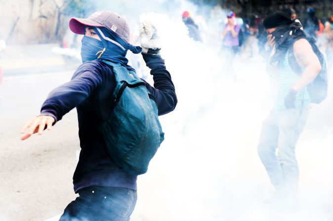 Uno de los manifestantes devuelve una lata de gas lacrimógeno a la GNB.