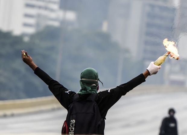 Un manifestante con una bomba molotov desafía a las fuerzas de seguridad.