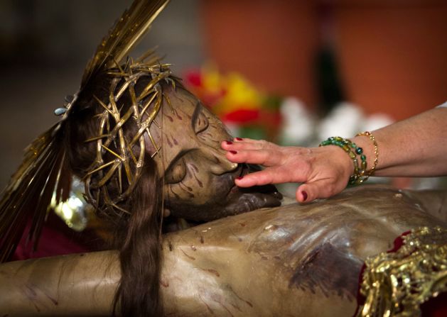 Una persona toca la escultura del Cristo de la Sangre durante una procesión de Semana Santa en Palma de Mallorca el 13 de abril de 2017.