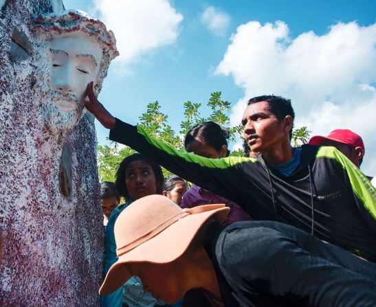 Cristianos devotos de Timor Oriental tocan una figura que representa a Jesucristo mientras oran durante una procesión de Semana Santa hacia una un santuario religioso en las colinas de Comoro en Dili el 14 de abril de 2017.