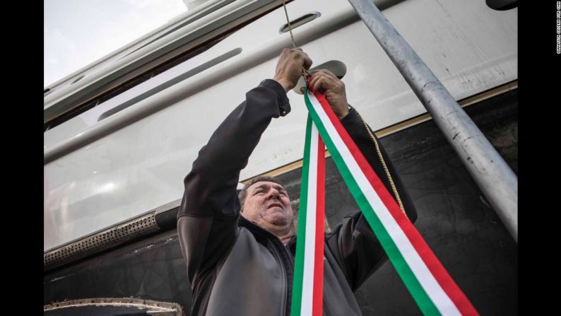 Un empleado del astillero asegura cintas de los colores de la bandera italiana que ayudarán al tradicional rompimiento de una botella de champaña contra el casco del Aurora durante la ceremonia de inauguración.