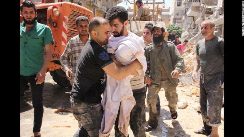 El padre de una niña de 3 meses llora con su bebé en brazos después de que fuera sacada de los escombros.