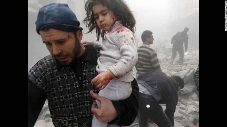Un hombre carga a un niño que encontró entre los escombros de un bombardeo en 2014.